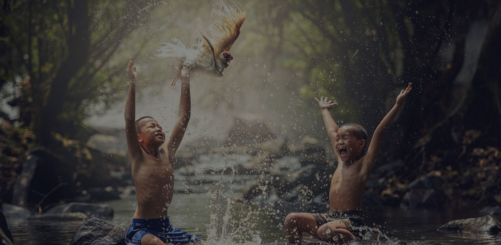 two boys playing in the water with a bird